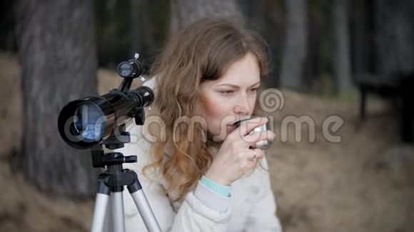 有魅力的女人在河岸的森林里通过望远镜看视频的预览图