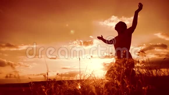 女人跪着祈祷女孩在日落时双手交叉祈祷剪影慢动作视频生活方式视频的预览图