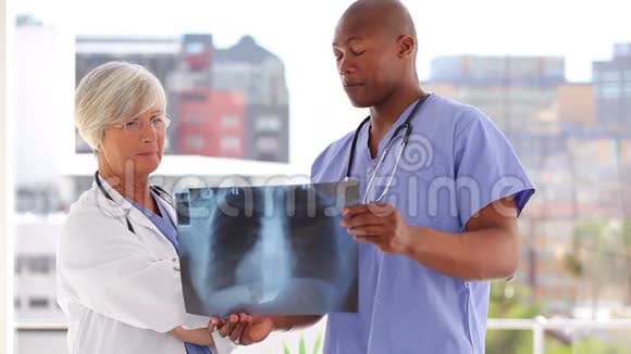 两个微笑的医生看着X光视频的预览图