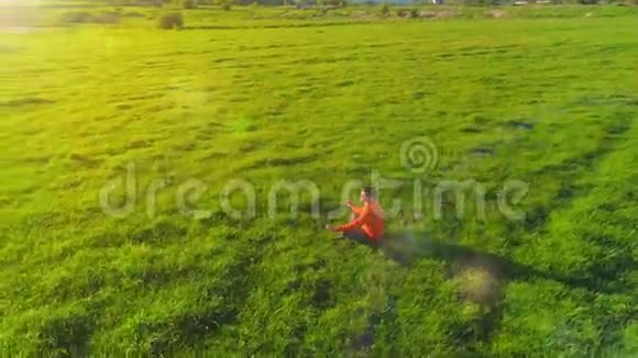 低空径向飞行超过运动瑜伽男子在完美的绿草在山上日落视频的预览图