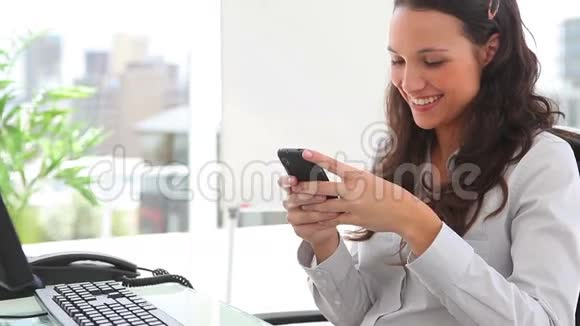 女商人一边写短信一边微笑视频的预览图