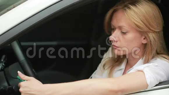 在车里用智能手机的漂亮女孩坐在车里的女孩视频的预览图