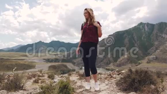 一位女游客在群山背景下的肖像带背包的旅行者视频的预览图