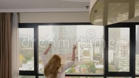 一个女人带着一个手提箱在摩天大楼的背景下在一个全景窗口视频的预览图