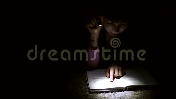 小女孩正在黑暗的房间里看一本带手电筒的书视频的预览图