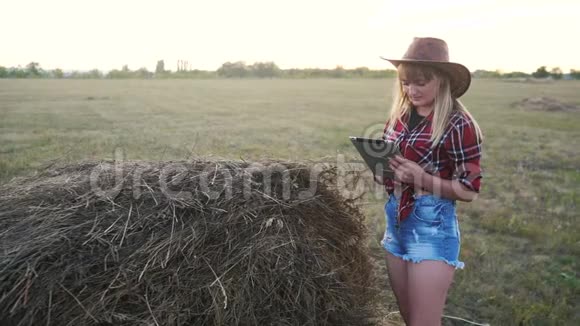 智慧农业慢动作视频概念女孩农学家在干草场生活方式堆里拿着平板电脑触摸板电脑视频的预览图