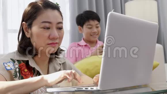 亚洲母子在笔记本电脑上微笑着看着视频的预览图