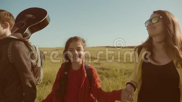 快乐家庭慢动作视频行走在大自然男孩女孩和妈妈在野外徒步旅行带吉他的游客视频的预览图
