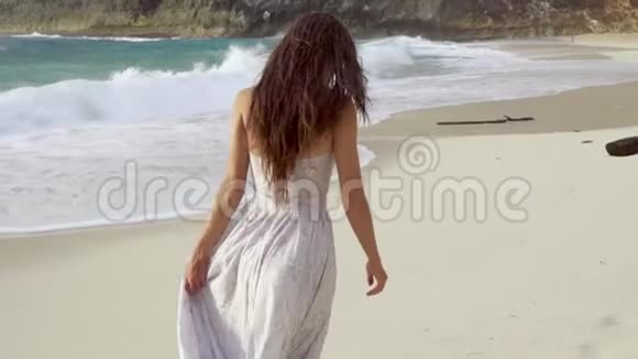 穿裙子的女人在海滩上散步视频的预览图