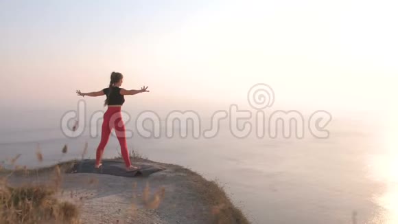 美丽的景色女人做瑜伽伸展在山上日落时的海景视频的预览图