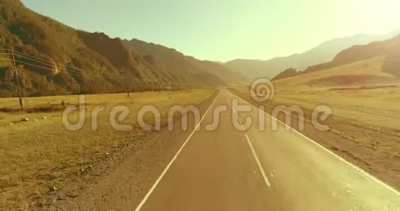 在阳光明媚的夏季早晨低空飞越山路和草地视频的预览图