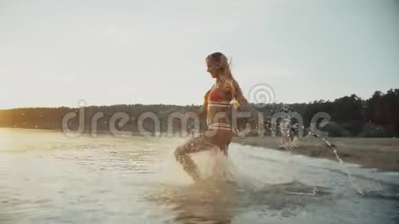 穿比基尼的女孩在美丽的海滩上洗澡视频的预览图