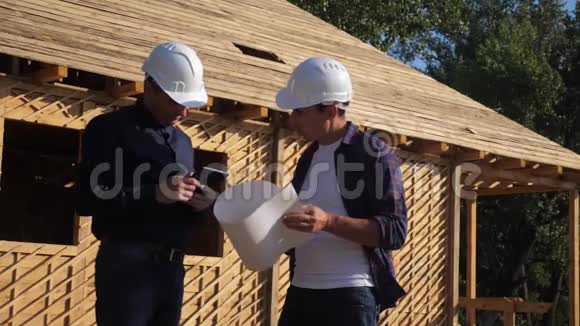 团队合作概念建筑构建建筑师慢动作视频两名戴头盔的建筑工人研究房屋计划视频的预览图
