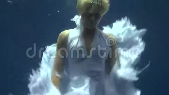 年轻女孩在红海的蓝色背景上模特水下白色天使服装视频的预览图