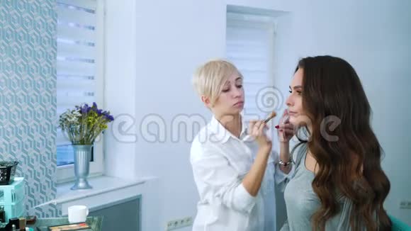 化妆师在美容院为年轻女性化妆视频的预览图