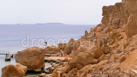 落基海滩与伞附近的悬崖在红海的珊瑚礁埃及视频的预览图