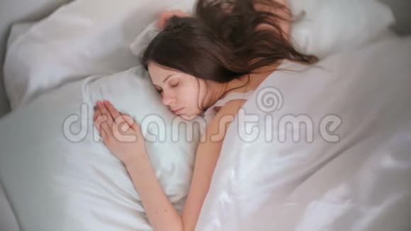 年轻的黑发女人睡在床上视频的预览图
