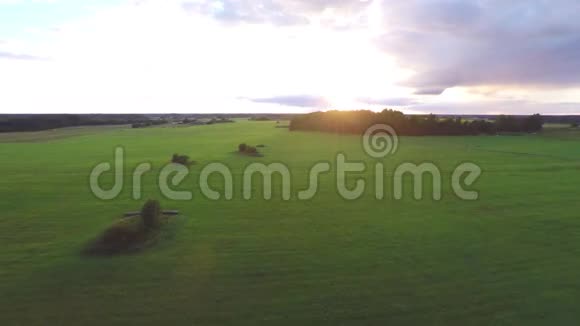 空中飞过郁郁葱葱的绿色田野和草地日落视频的预览图