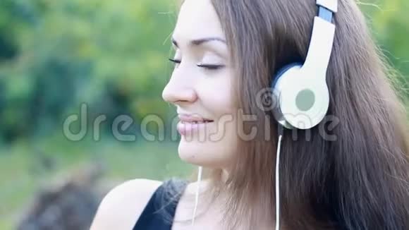 戴着耳机听音乐的女人肖像美丽的女孩面部特写视频的预览图