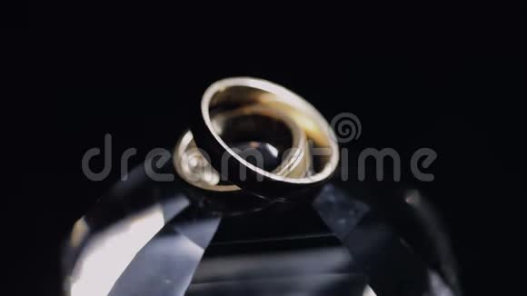 婚礼戒指躺在水晶上闪耀着光接近宏观黑色背景慢动作视频的预览图