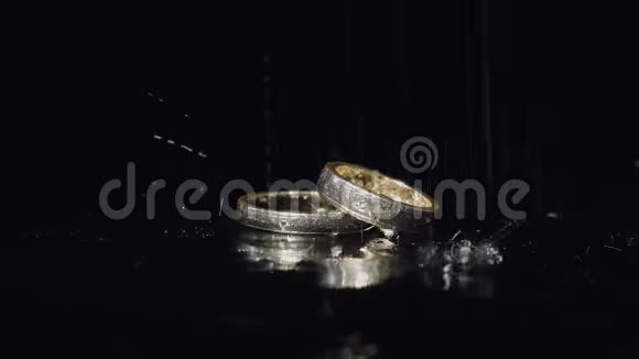 婚礼戒指躺在黑暗的表面闪耀着光接近宏观泼水视频的预览图