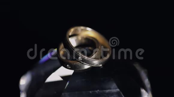 婚礼戒指躺在水晶上闪耀着光接近宏观黑色背景慢动作视频的预览图
