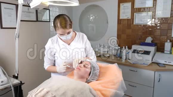 美容诊所手套美容师在女性皮肤上进行面部老化注射女人得到美容美容美容视频的预览图