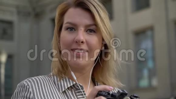 年轻的金发女郎微笑着在城市里摆姿势视频的预览图