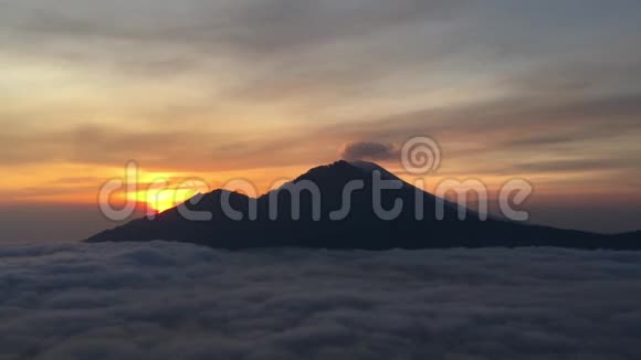 巴图尔湖上空的日出覆盖着云彩和阿贡火山喷发的烟雾从巴图尔山顶部看到在巴厘岛印度尼西亚视频的预览图