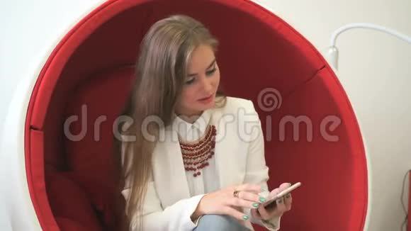 女客户坐在红色椅子上拿着智能手机视频的预览图