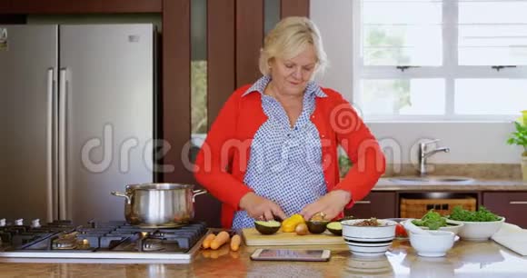 高级妇女在厨房切菜视频的预览图
