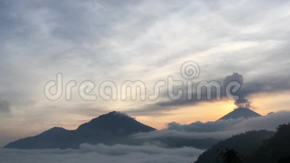 巴图尔湖上空的日出覆盖着云彩和阿贡火山喷发的烟雾从巴图尔山顶部看到在巴厘岛印度尼西亚视频的预览图