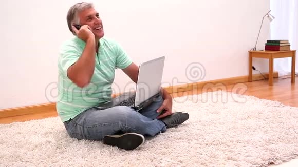 成熟男人坐在地毯上用笔记本电脑视频的预览图