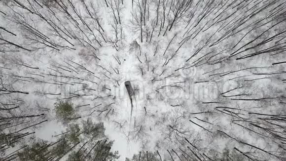 在冬季森林中乘雪覆盖道路的越野车6x6上的空中观景俯视视频的预览图