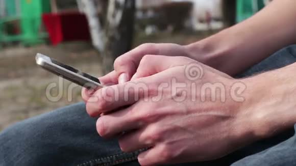 带着白色电话的年轻人坐在街上公园里户外视频的预览图