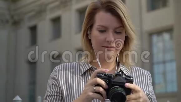 年轻的金发女郎微笑着在城市里摆姿势视频的预览图
