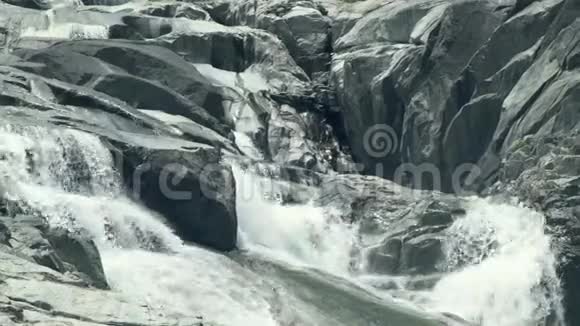 河流在山瀑布的大石头上流淌山岩河的流水景观视频的预览图
