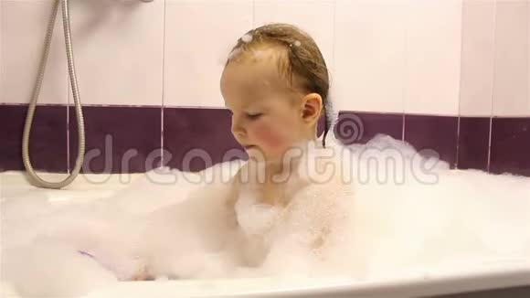小快乐女孩在浴室里用泡沫洗澡他玩泡沫视频的预览图