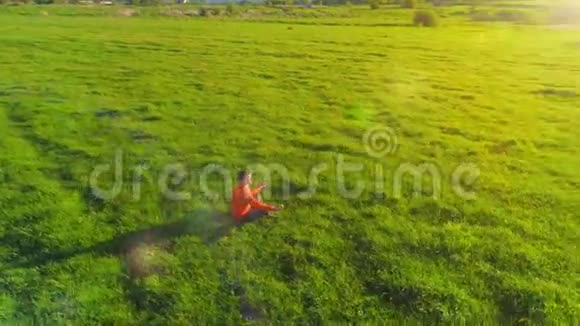 低空径向飞行超过运动瑜伽男子在完美的绿草在山上日落视频的预览图