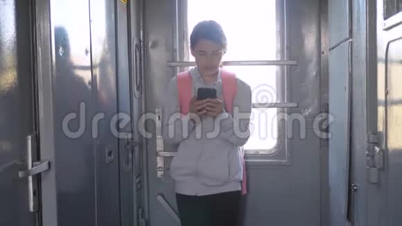 年轻的生活方式女孩旅行者带着背包站在火车的窗户边带着智能手机旅费视频的预览图