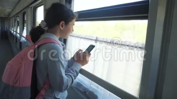 带背包的少女旅行者站在生活方式的窗户旁火车上有一部智能手机旅费视频的预览图