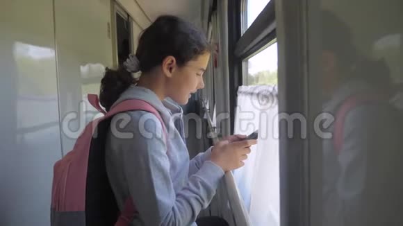 带背包的少女旅行者站在装有智能手机的火车车窗旁旅费视频的预览图