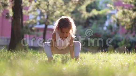 小可爱的女婴在公园的草地上做瑜伽运动视频的预览图