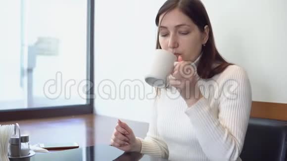 一个在咖啡馆里喝酒的布鲁内特女人视频的预览图