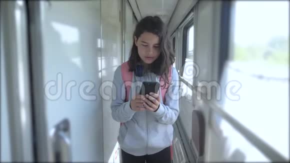 十几岁的女孩走在火车车厢里带着生活方式背包和智能手机交通运输视频的预览图
