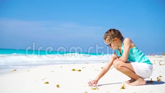 暑假期间海滩上可爱的小女孩在沙滩上画画视频的预览图