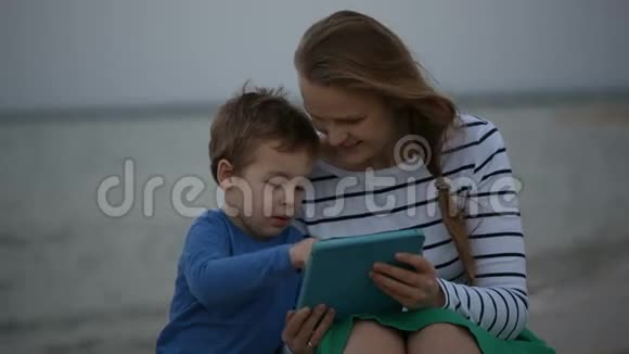 母亲和儿子坐在海边视频的预览图