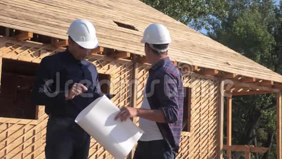 团队合作概念建设构建建筑师慢动作视频两个戴头盔的建筑工人研究房屋计划视频的预览图