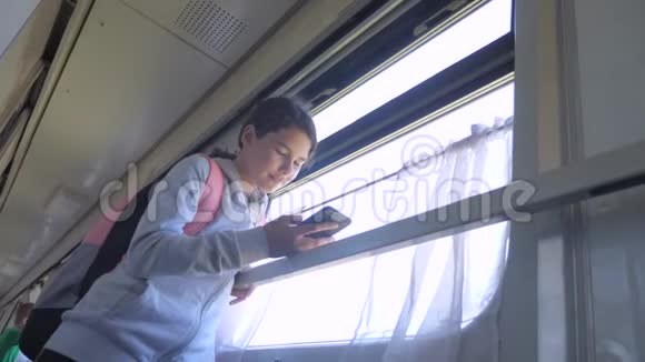 带背包的少女旅行者站在生活方式旁边车窗上放着智能手机旅费视频的预览图