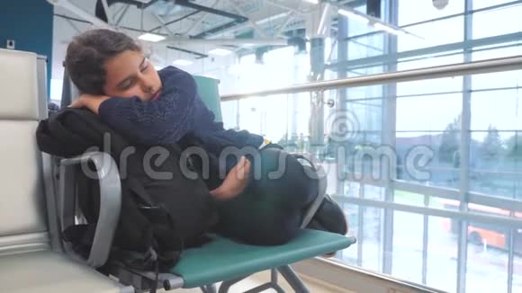 疲惫的少女少年旅行者睡在机场等待飞机起飞生活方式大门长椅与她所有视频的预览图